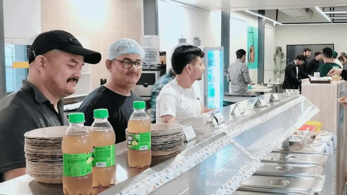 Three members of the counter team working the service line during a busy service, with guests seated behind them.
